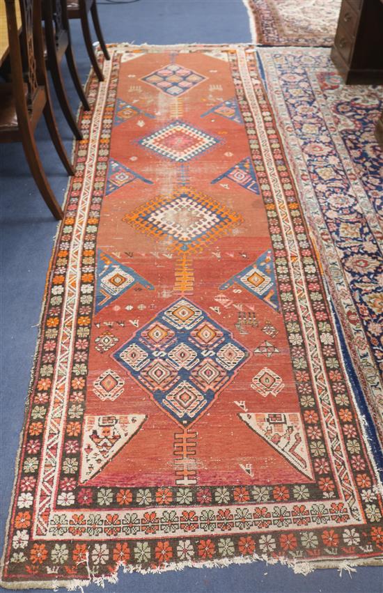 A Karabagh runner, woven with four lozenge medallions on a wine red ground with triple border, (worn) 340cm x 110cm